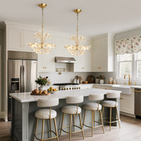 Two brushed gold glass flower chandeliers hanging above a kitchen island