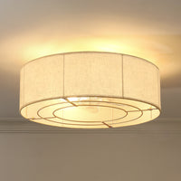 Gold linen-blend flush mount ceiling fan with light illuminated on the ceiling