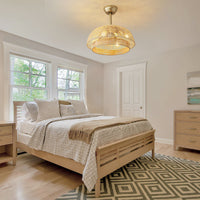 Gold rattan caged ceiling fan with light installed in a bedroom with a wood bed and patterned rug