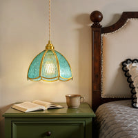 Blue water ripple glass pendant light with gold frame hanging beside a bedroom nightstand