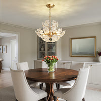 Brushed gold glass flower chandelier centered above a round dining table