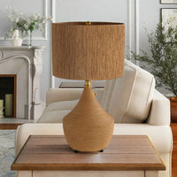 Natural rattan table lamp with vase-shaped woven base styled in a bright living room