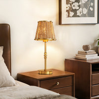Gold rattan table lamp on a bedroom nightstand beside a bed