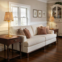 Gold rattan table lamp on a living room side table beside a sofa