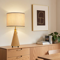 Single farmhouse rattan-finish table lamp with beige linen shade styled on a wooden console cabinet