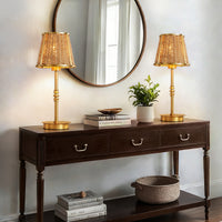 Gold rattan table lamp styled on a console table beneath a round wall mirror