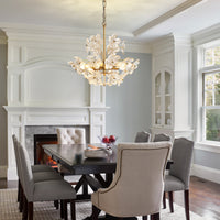 Brushed gold glass flower chandelier hanging above a dining table in a bright dining room