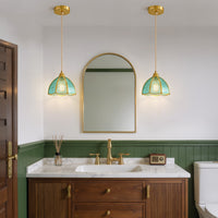 Two blue textured glass pendant lights with gold frames shown beside a vanity mirror