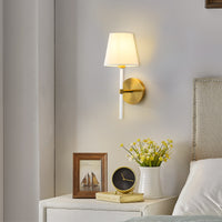 Matte gold linen shade wall sconce above a console table