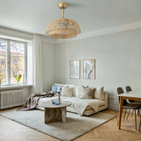 Gold boho rattan ceiling fan with light installed in a bright living room near a sofa and dining area