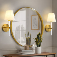 Matte gold linGolden shade wall sconces set of 2 beside a round mirror