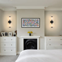 Matte black ribbed glass wall sconces beside a bedroom fireplace